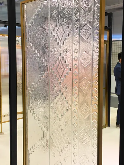 A tall patterned glass door panel in a brass frame, on show at an exhibitor stand.