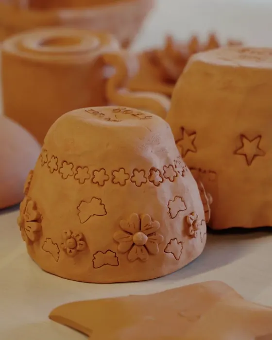 Cover of a Ceramic Cube reel: hand-built terracotta pieces decorated with flowers and stars on a studio table.